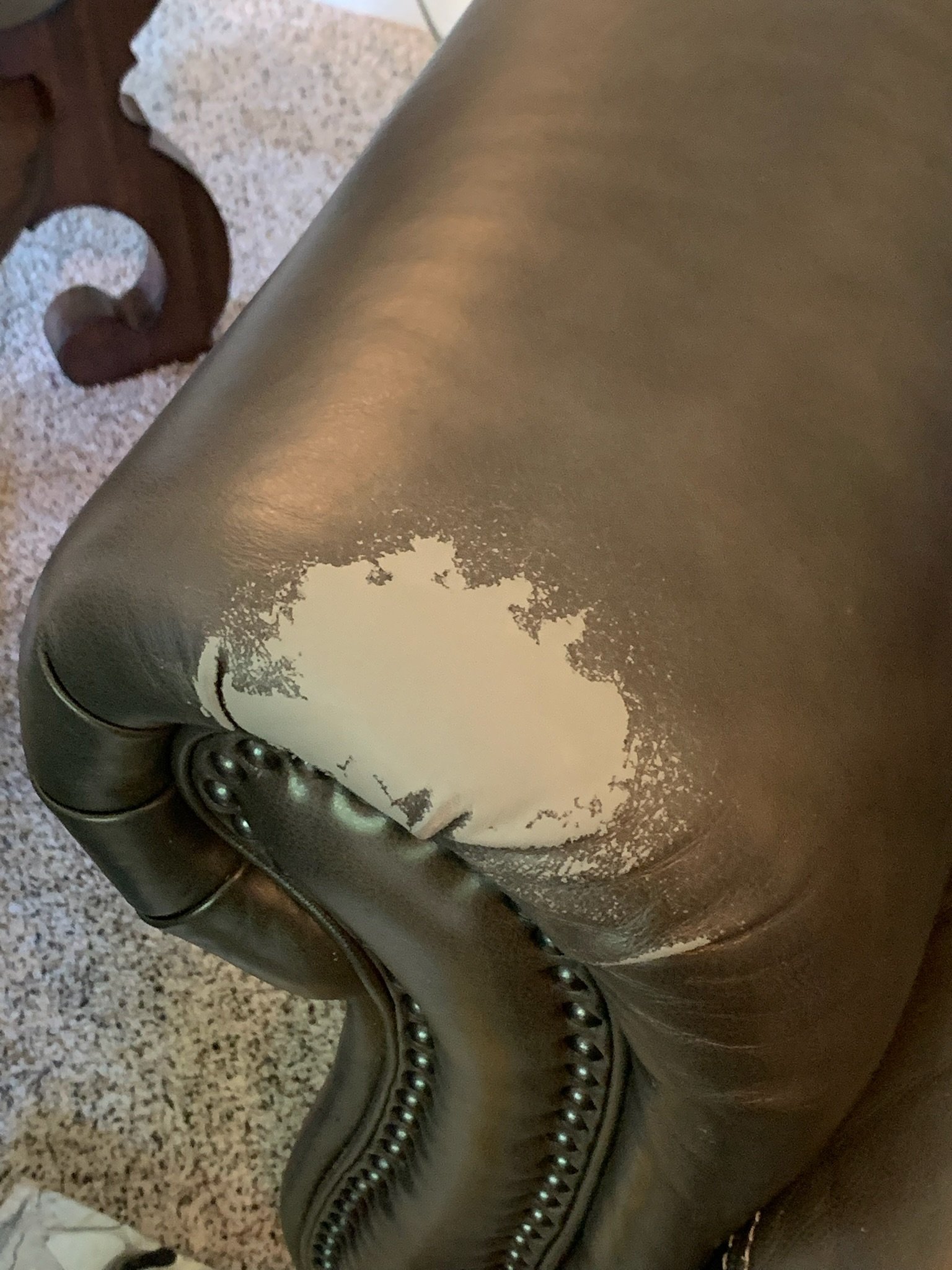 Hand spot on the arm of a lounge chair. This happens when you slowly wipe the top dye layer off and you can see the base color layer. This happens with hand oils being transfered onto the leather arm. 