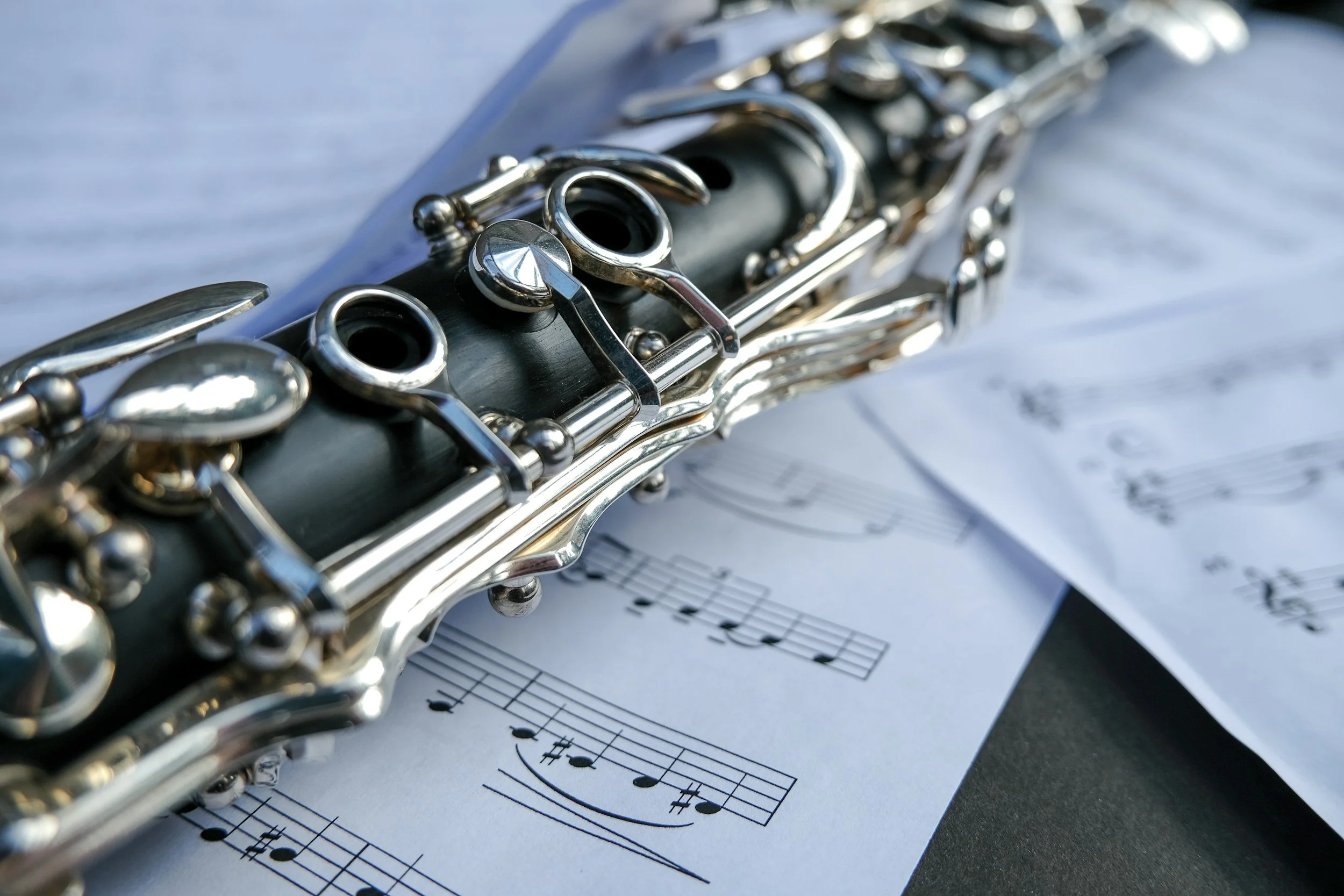 Close-up of a clarinet resting on sheet music with musical notes.