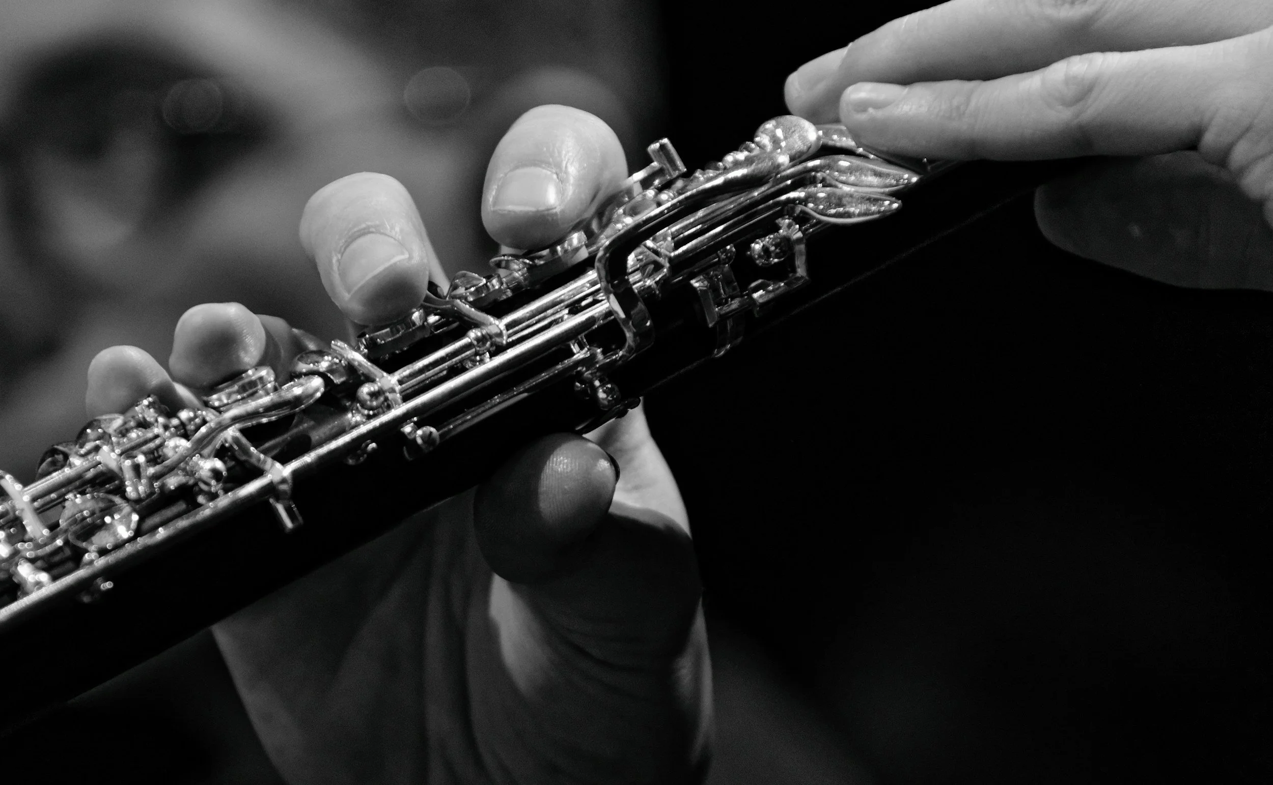Close-up black and white photo of a person's hand holding an oboe.