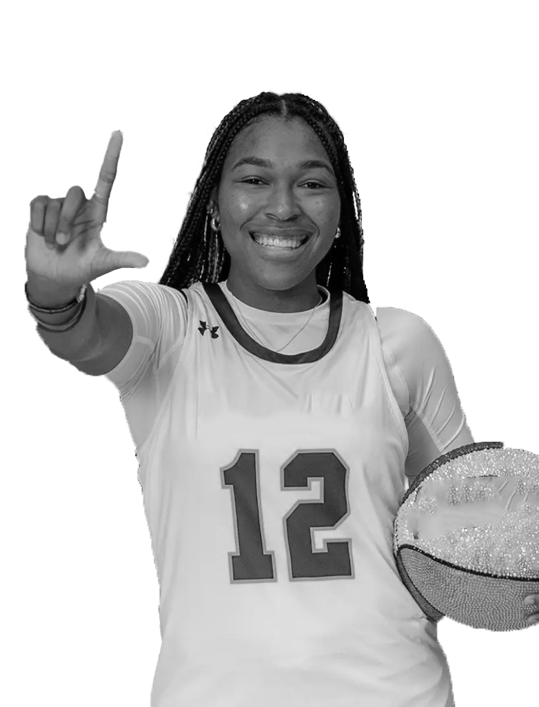 A young woman in a basketball uniform holding a Wilson basketball stands in a gymnasium with a basketball hoop behind her. She is smiling at the camera.