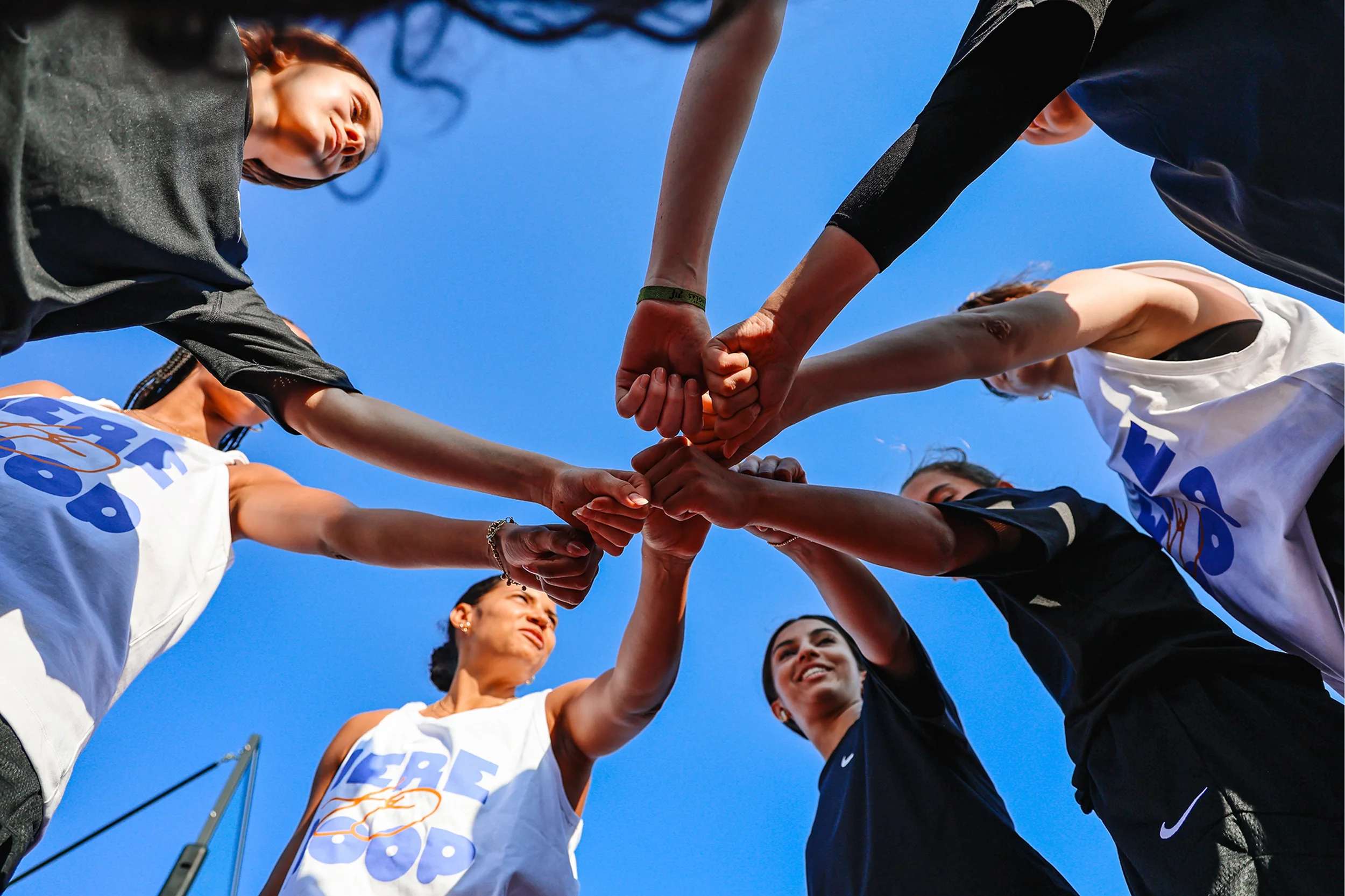 An indoor concert or event space with colorful lighting, fluffy cloud-like decorations hanging from the ceiling, and a large digital screen displaying the words 'LOST IN MUSIC' with a vibrant, multi-colored background. There are also artificial trees illuminated with multi-colored lights in the background, creating a whimsical, immersive atmosphere.