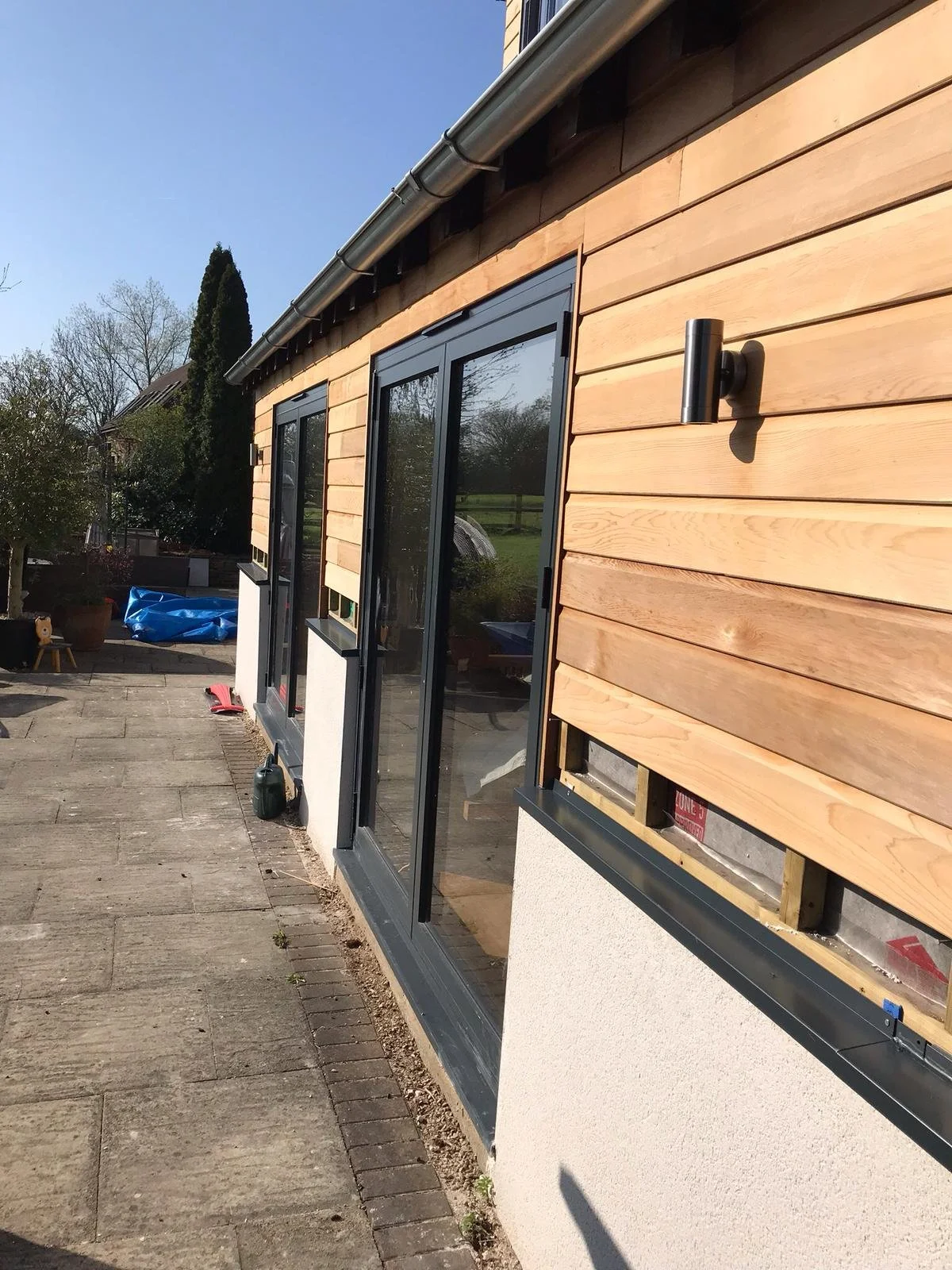 Empty room with unfinished walls, a large sliding glass door, and a skylight, in a house under construction.