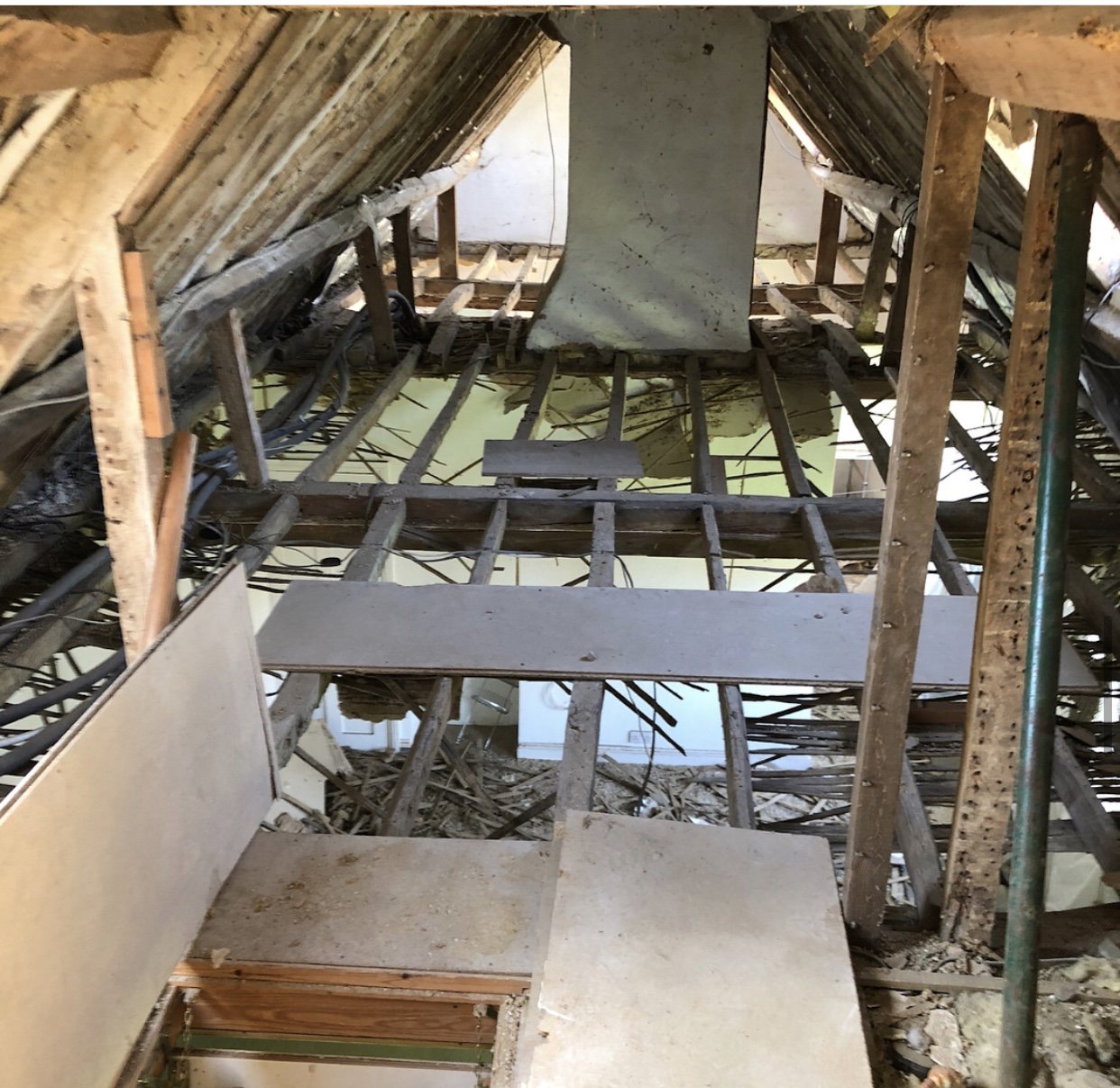Attic with exposed wooden beams, scaffolding, and wiring, under renovation.