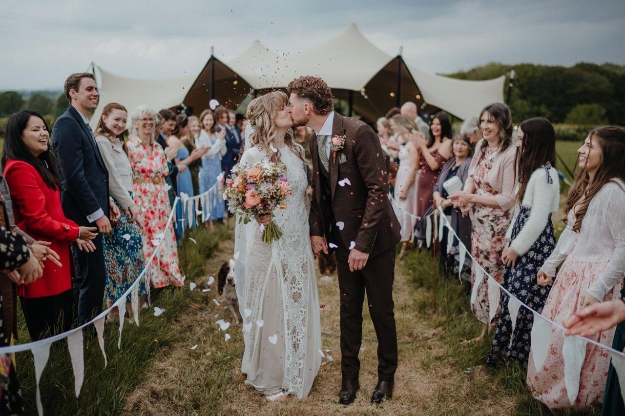 A happy couple walking from the marquee after just being married