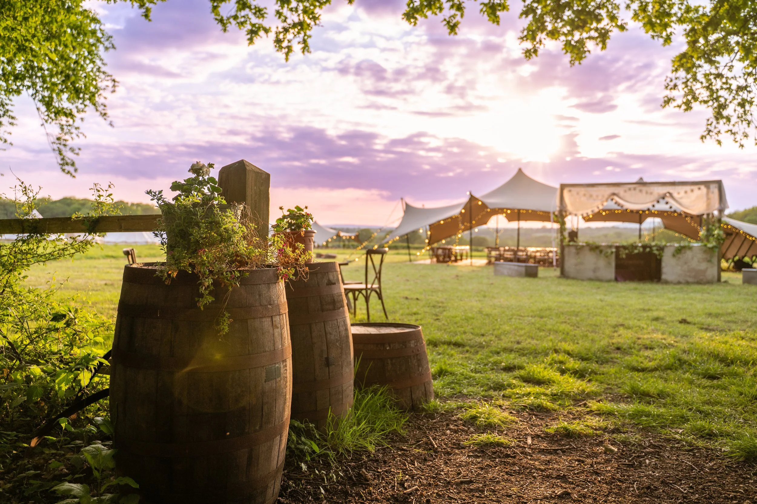 Barrels in foreground with view of marquee in the field