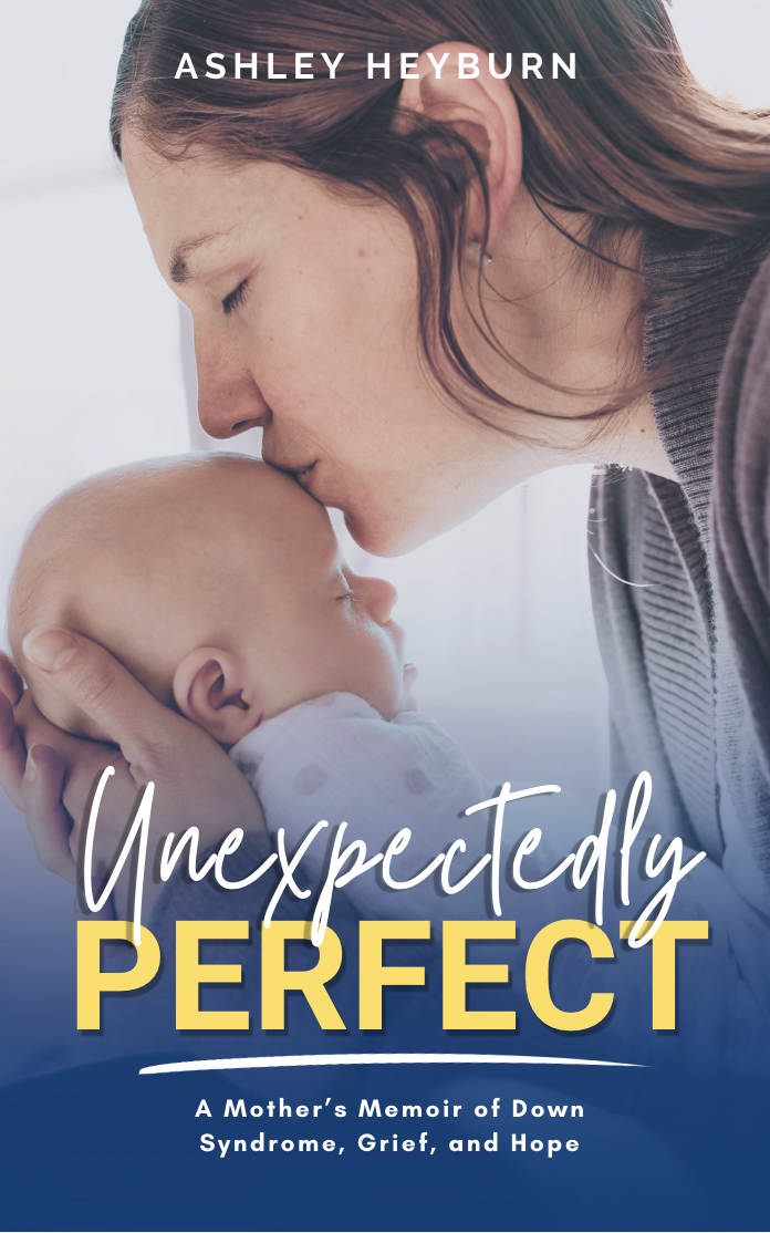 A woman gently kisses a baby's forehead, with the woman's eyes closed and the baby's face turned upward. The cover text includes the author Ashley Heyburn and the title "Unexpectedly Perfect," along with a subtitle "A Mother's Memoir of Down Syndrome, Grief, and Hope."