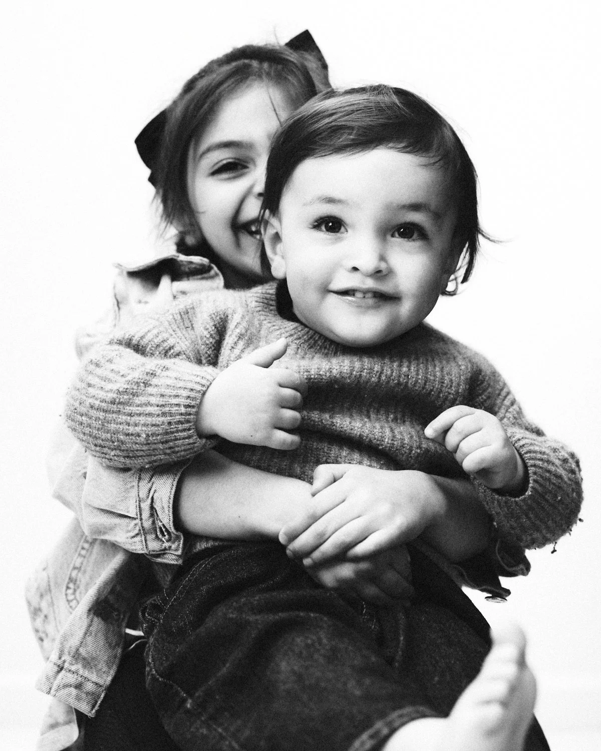 Black and white photo of a woman holding a young girl and a young boy, all smiling. Photographed in monochrome by Madivan Studios in New York City.