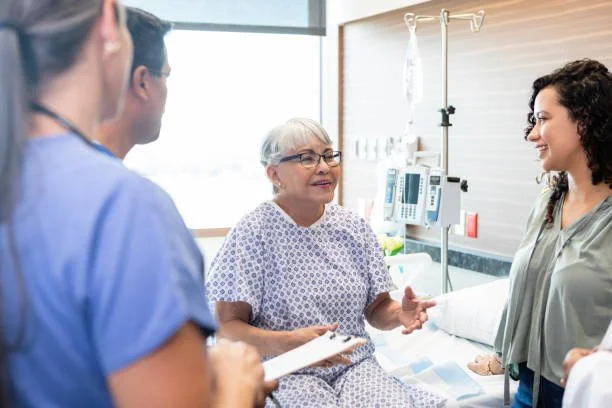 Hospital room with a woman patient talking to two nurses.