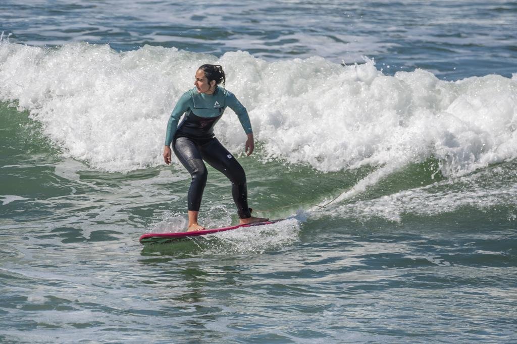 Person surfing on a wave with a red surfboard and wearing a wetsuit. Porto Surf Femmes,  photography by Abilio Meneses