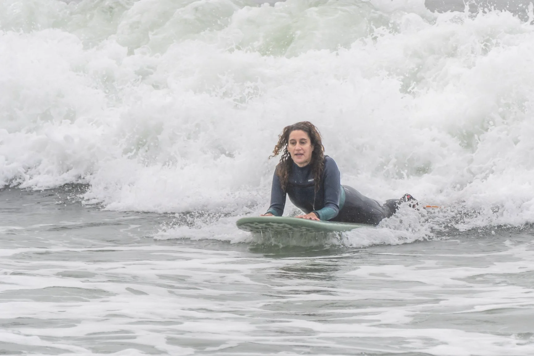 Woman surfing on a wave on a surfboard, wearing a wetsuit. Porto Surf Femmes,  photography by Abilio Meneses