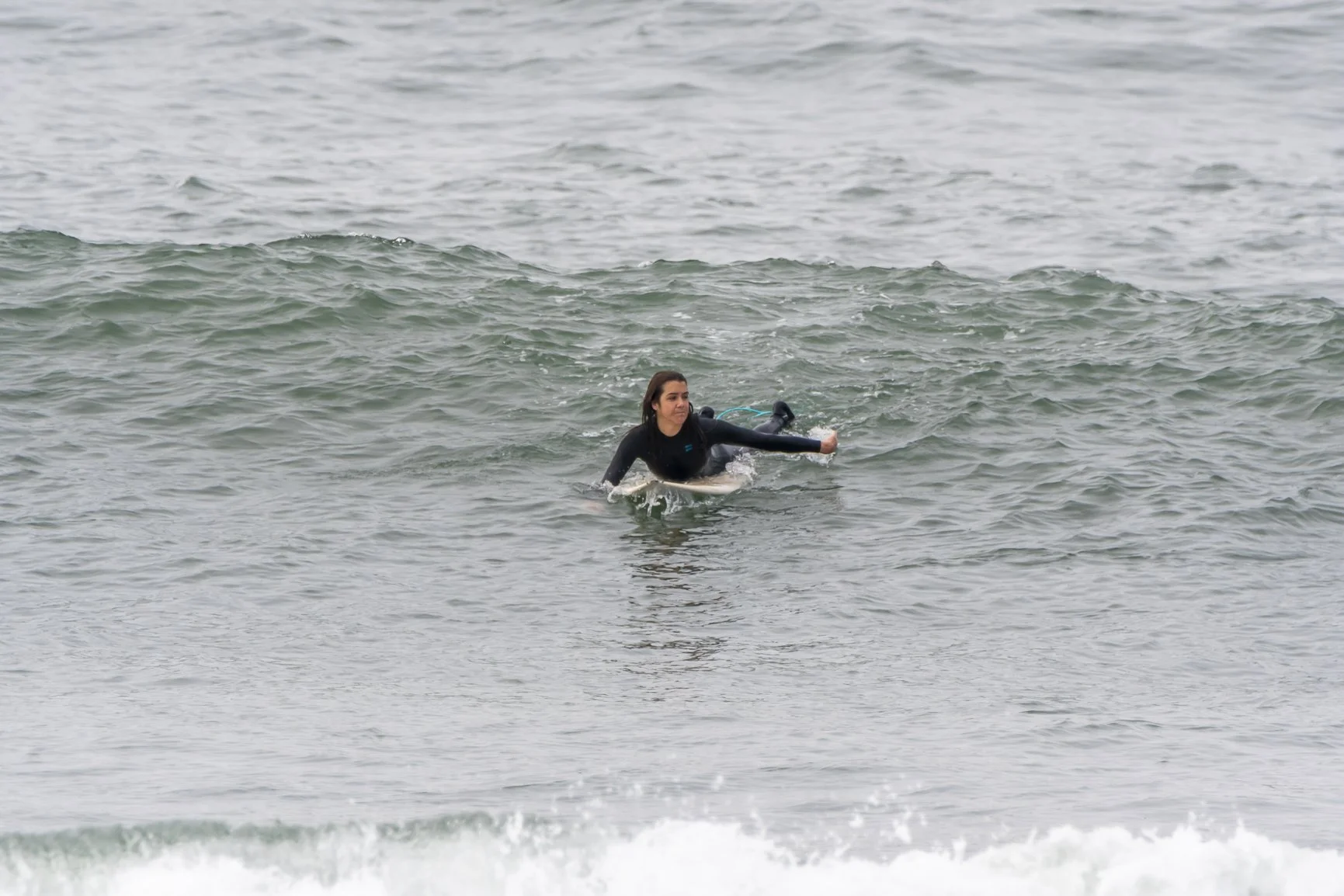 Surfer paddling on a surfboard in ocean waves. Porto Surf Femmes,  photography by Abilio Meneses