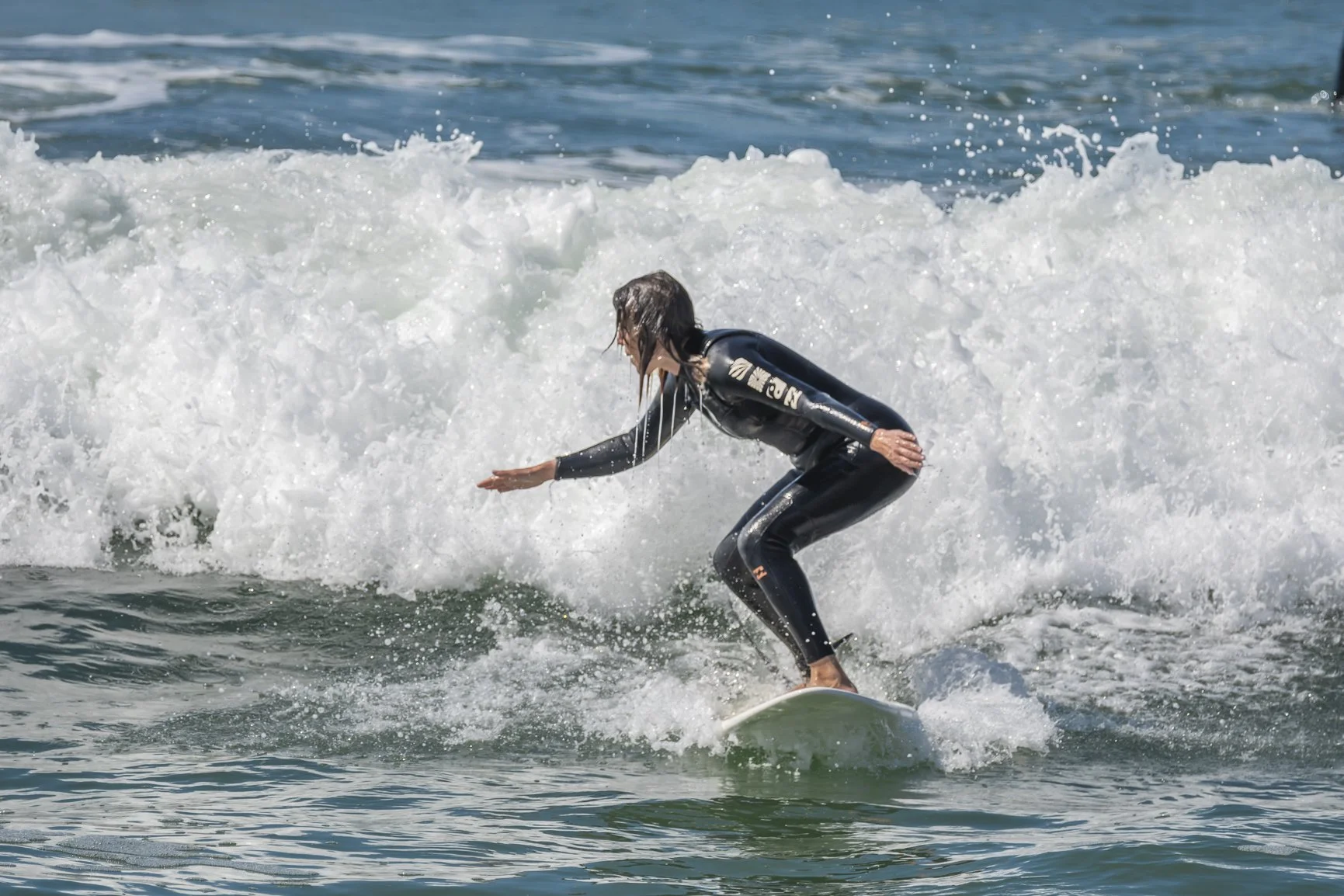Surfer in black wetsuit riding a wave in the ocean. Beginner surfer. Porto Surf Femmes,  photography by Abilio Meneses