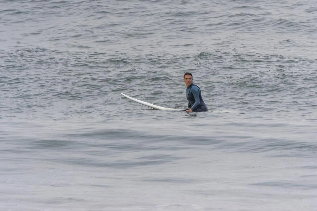 Surfer in wetsuit holding surfboard in ocean. Porto Surf Femmes,  photography by Abilio Meneses
