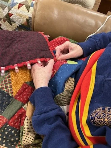 Person sewing a quilt with various colorful fabric patches.