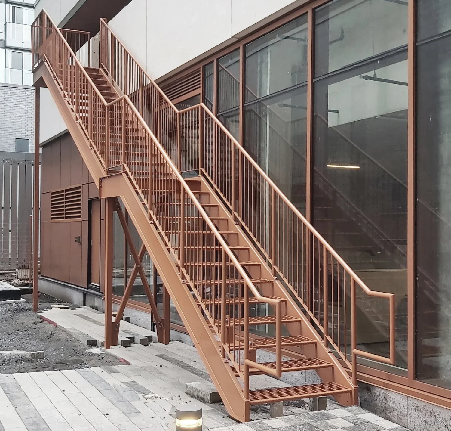 Escalier de sortie commerciale extérieure à double volée avec garde-corps, installé sur la façade d'un bâtiment moderne à Montréal.