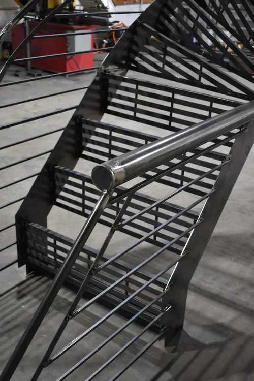 Marches et garde-corps d'un escalier industriel en acier noir fabriqués sur mesure dans l'atelier de PAM métal Inc.