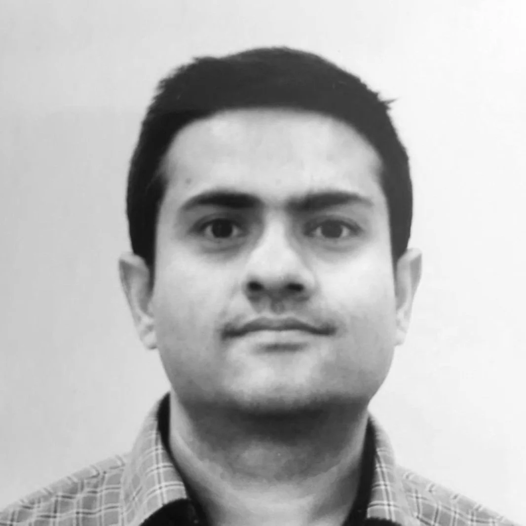 Black and white portrait of a man wearing a checkered shirt, facing forward.