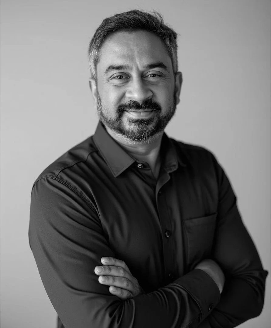 Portrait of a man in a suit and dress shirt, smiling, black and white photograph.