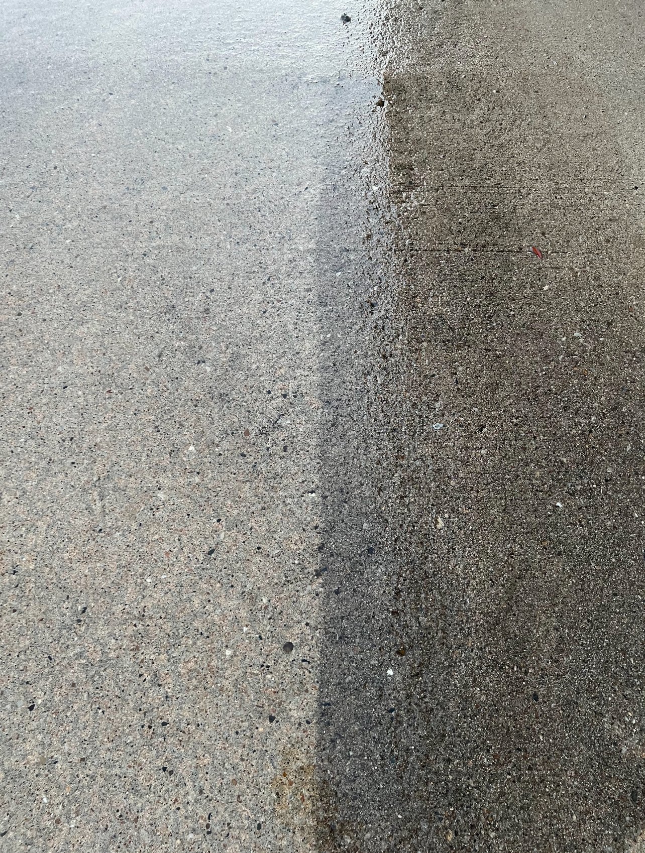 Close-up of a concrete sidewalk, showing a clear division between light and dark gray pavement.