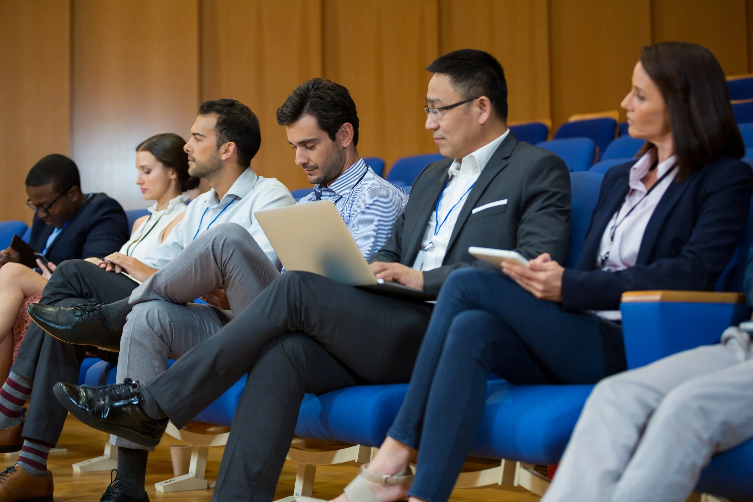 People sitting in a conference room, engaged with laptops and tablets.