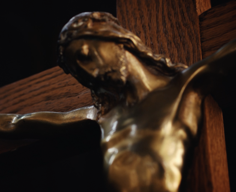 Close-up of a bronze crucifix sculpture of Jesus Christ on a wooden cross