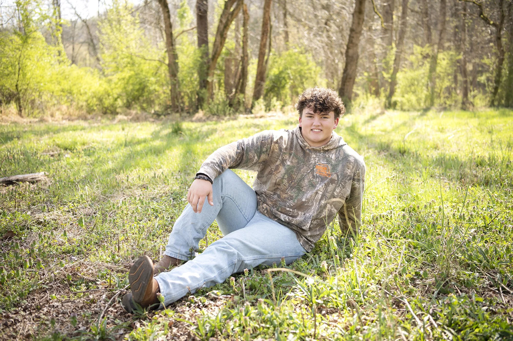 High school senior portrait session of Jacob Sluss captured in natural light on a farm in Woodstock Georgia featuring relaxed candid posing and true-to-color editing.