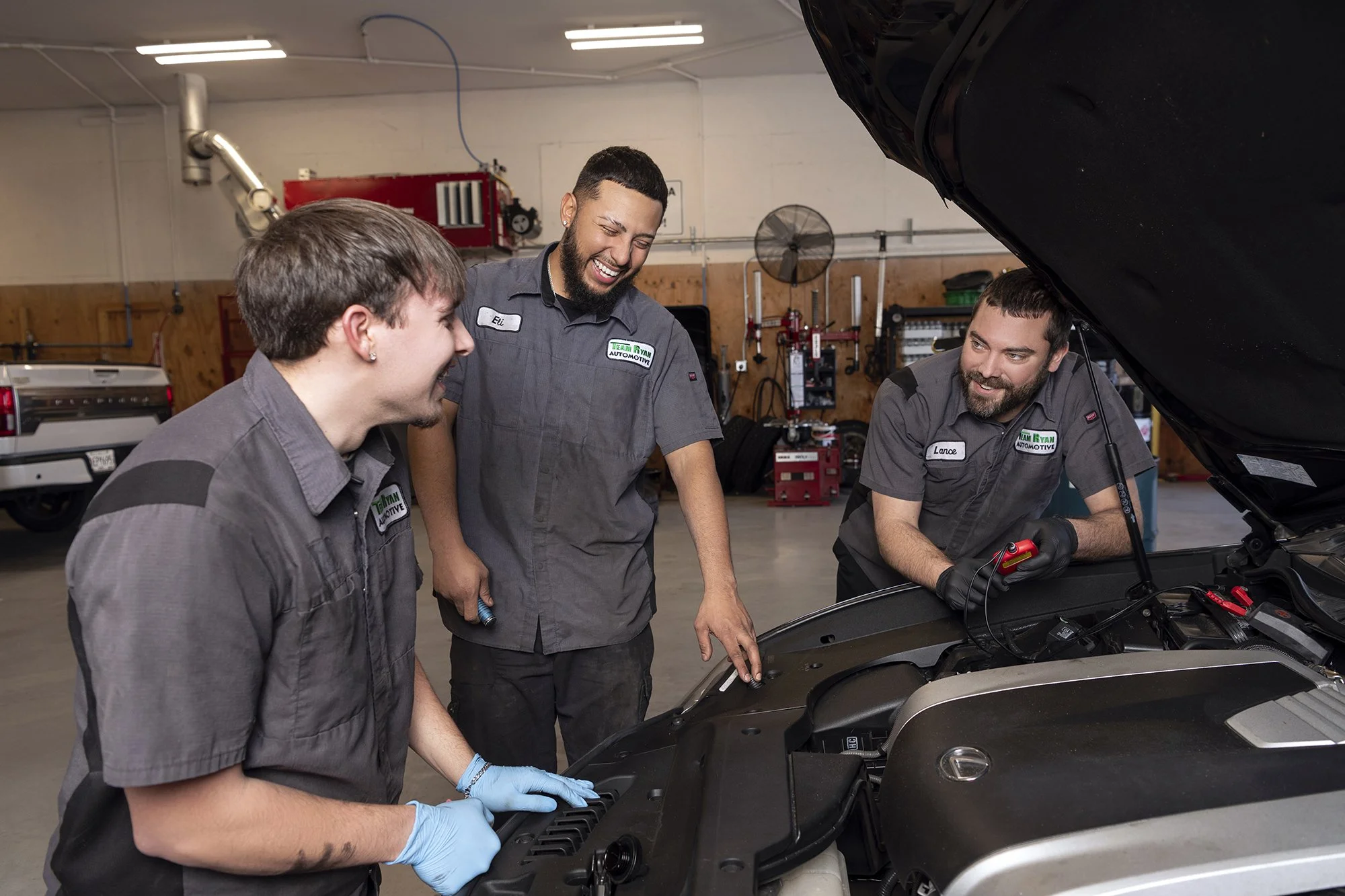Professional branding and team photography for Team Ryan Automotive captured inside their clean and modern automotive shop using on-site studio lighting.