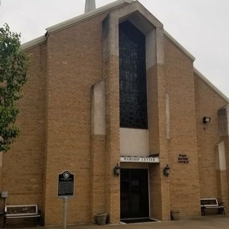 Front entrance of a brick church building with a large window and sign reading 'Worship Center'