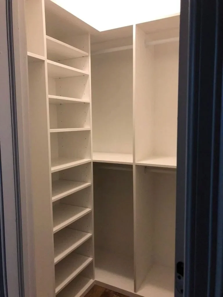 Empty walk-in closet with white shelving and hanging rods, viewed from the entrance.
