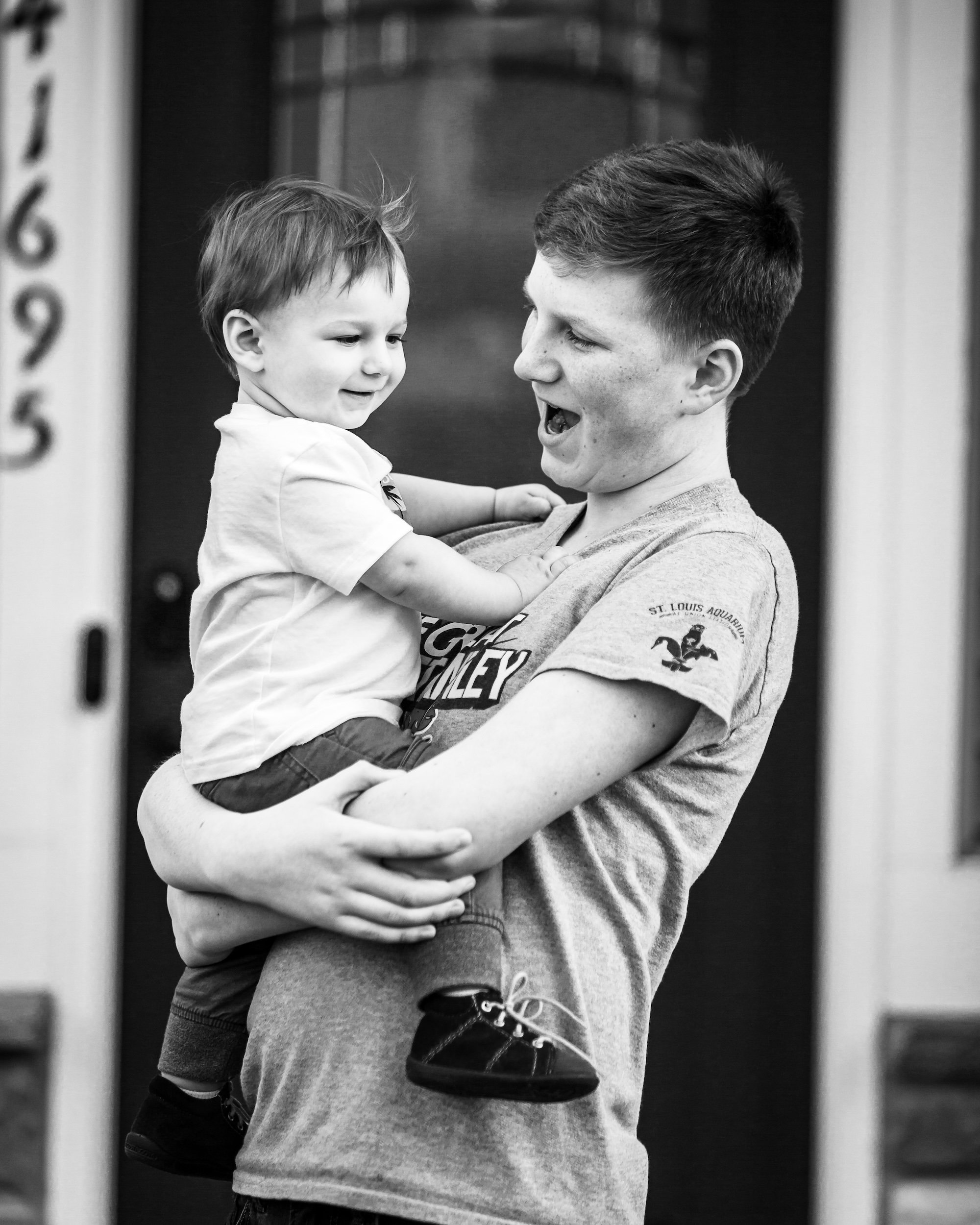 Teenage boy holding his younger brother and both smiling