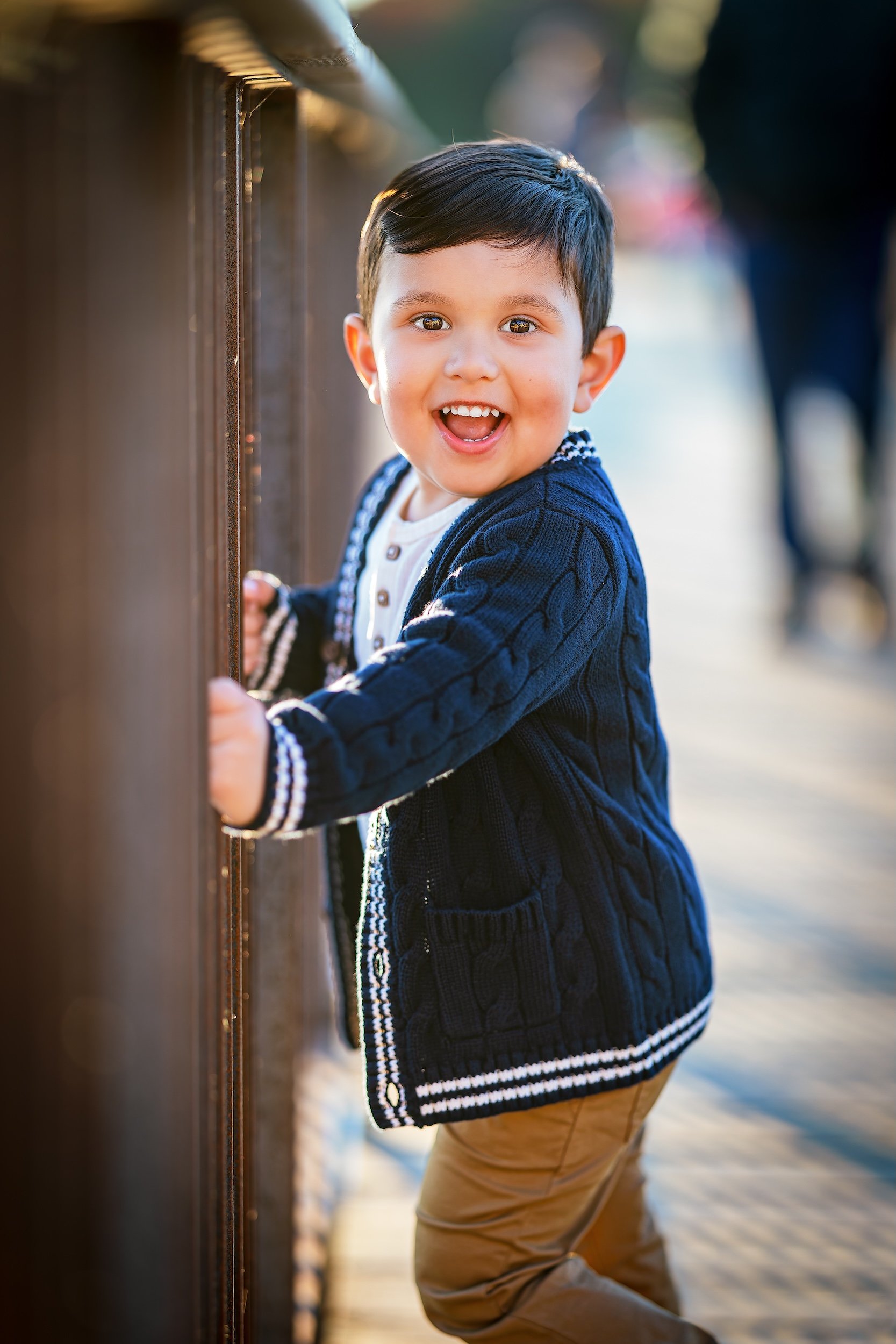 Young boy smiling and holding onto the side of a bridge