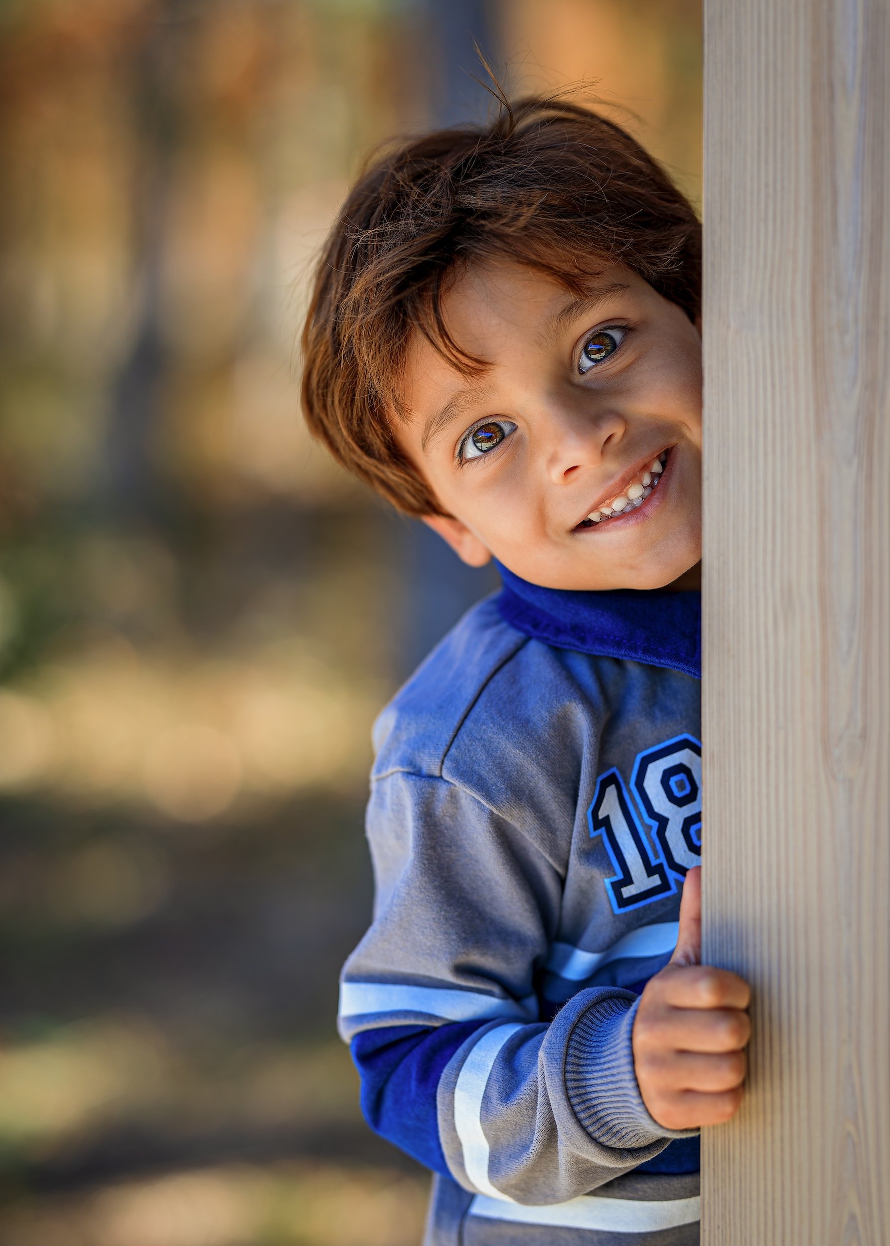 Boy peaking around a post and smiling