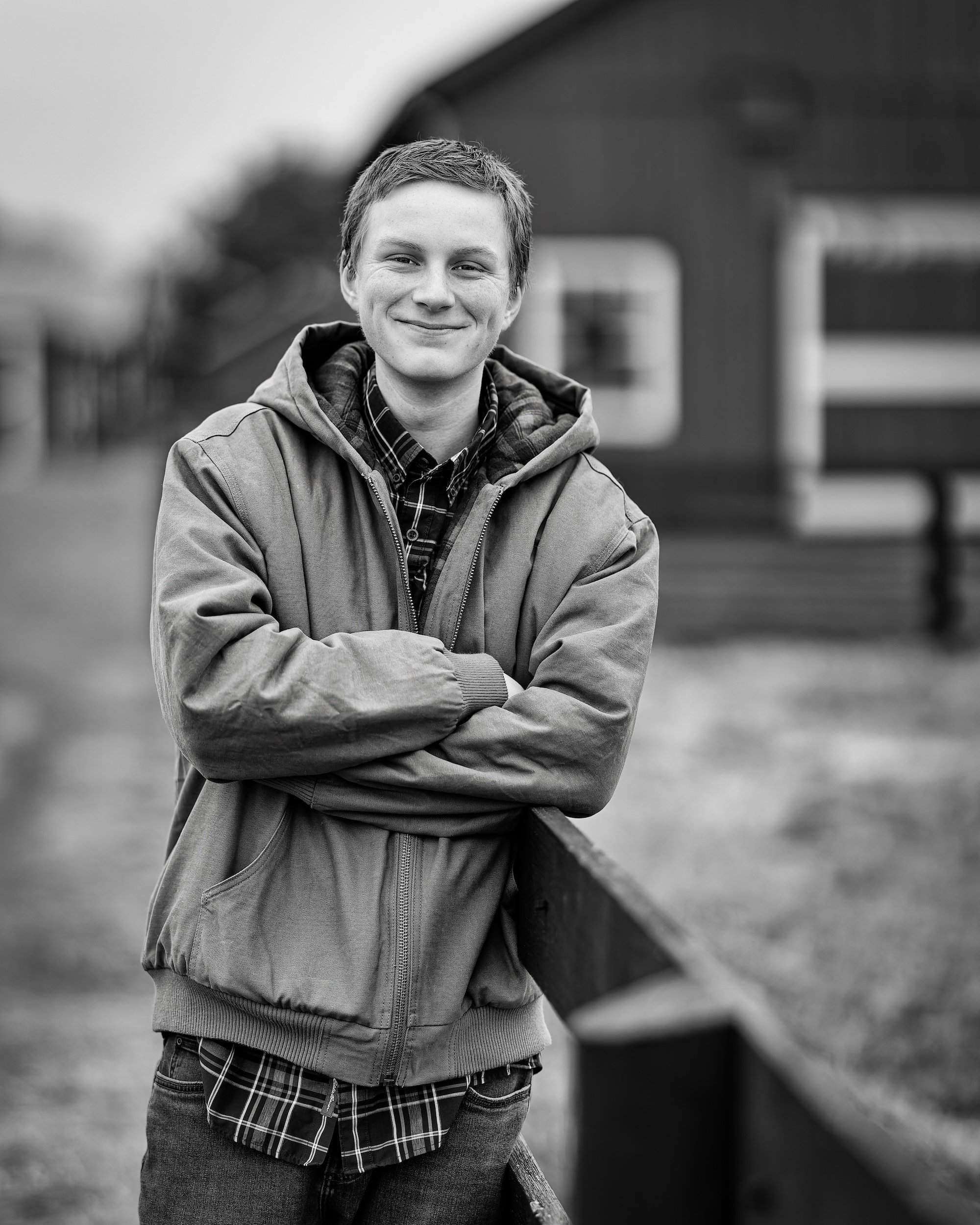 Boy smiling with arms crossed and a barn in the background