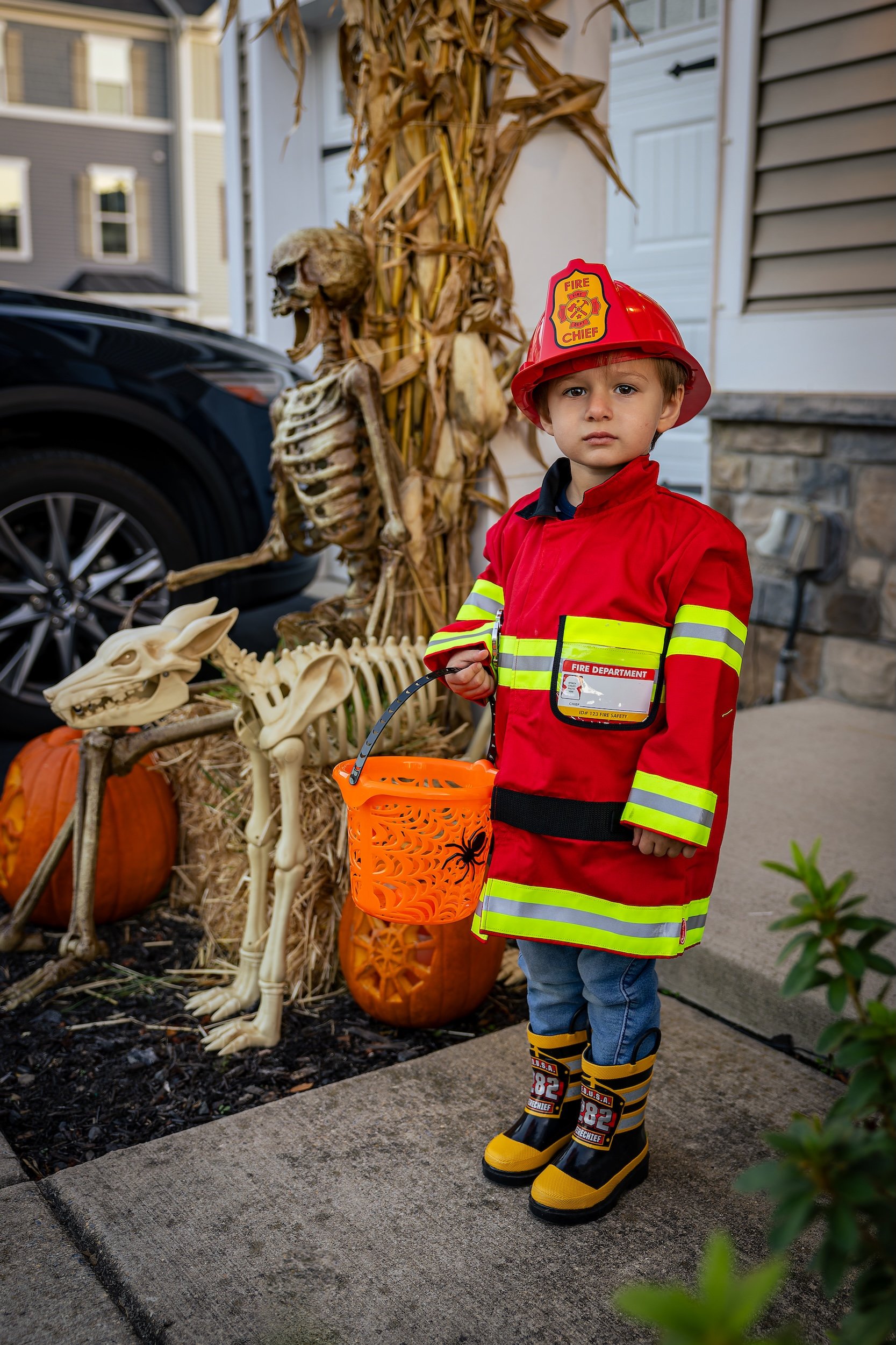 Young boy in a firefighter costume outside of his home for Halloween