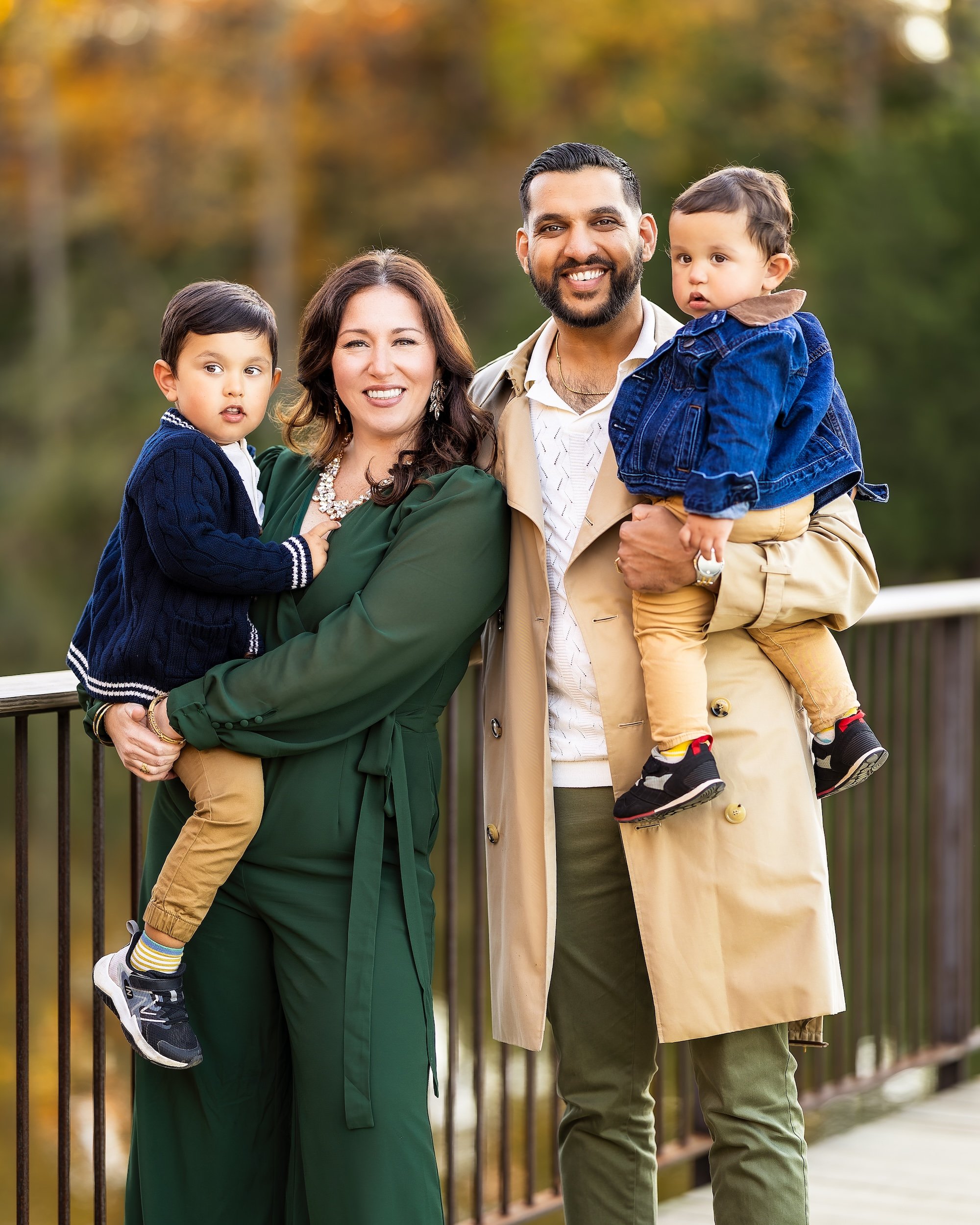 Mom and Dad posing holding their two young sons and smiling