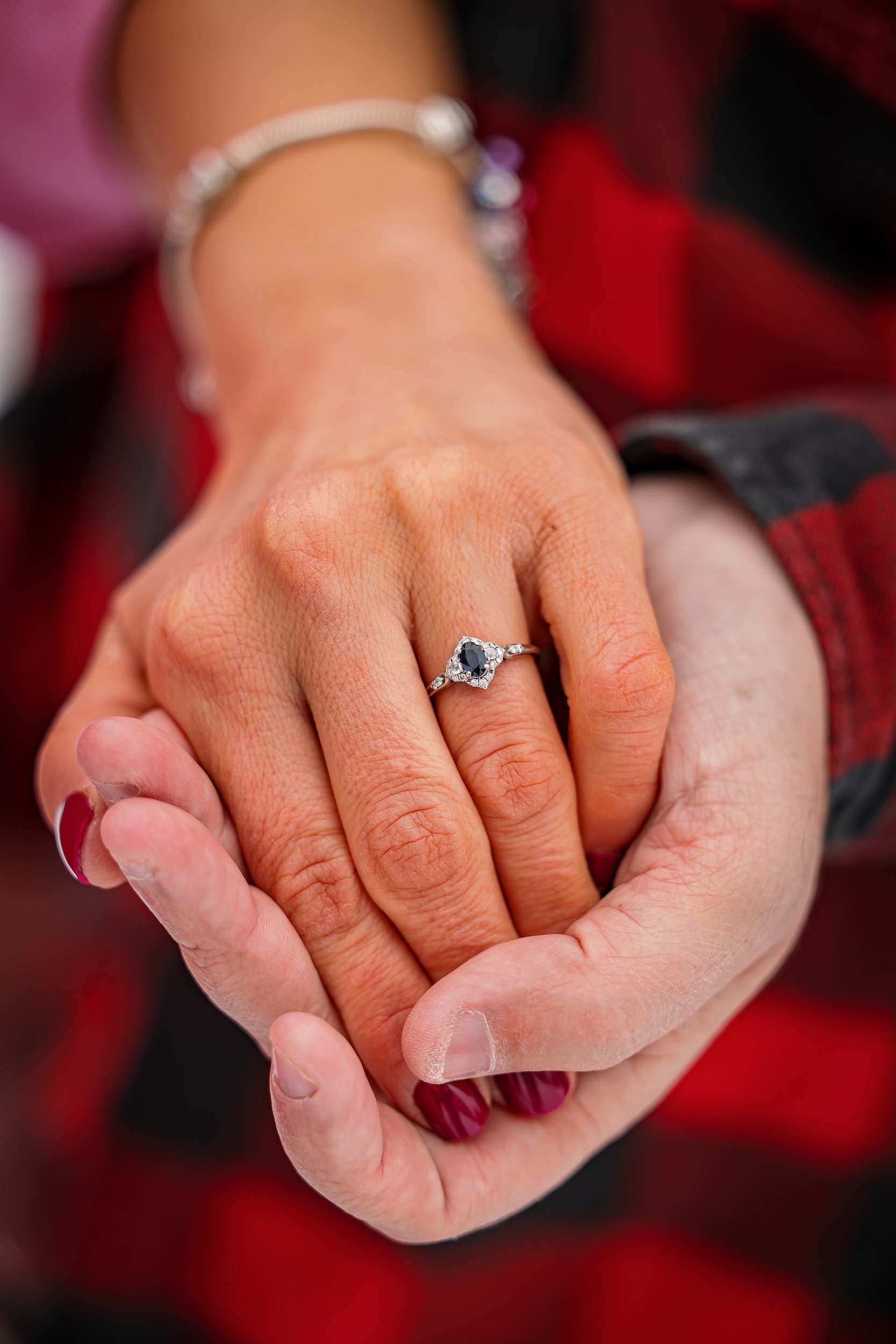 Man holding a his fiancé's hand showing the engagement ring