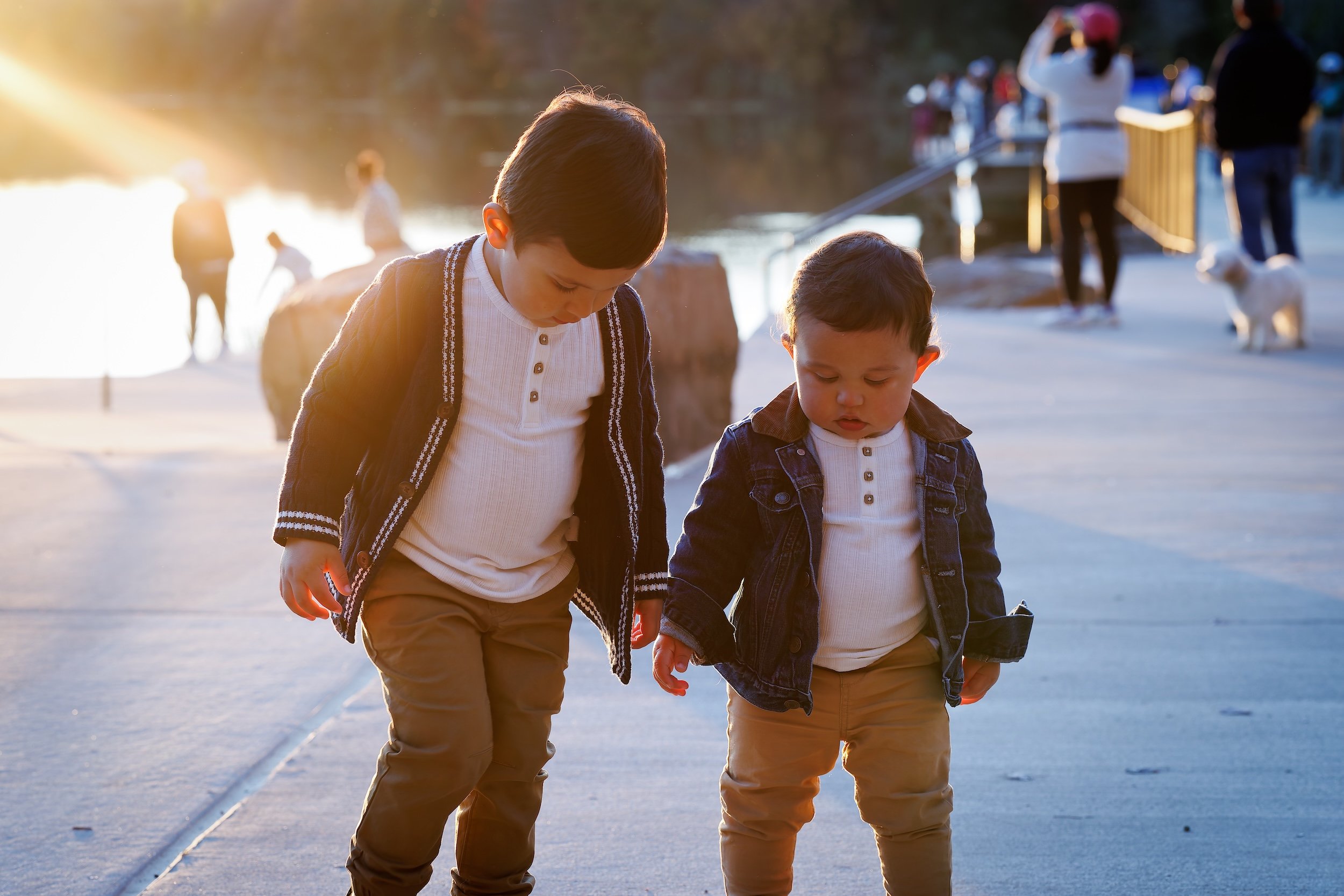 Two young brothers walking together with the sun setting in the background