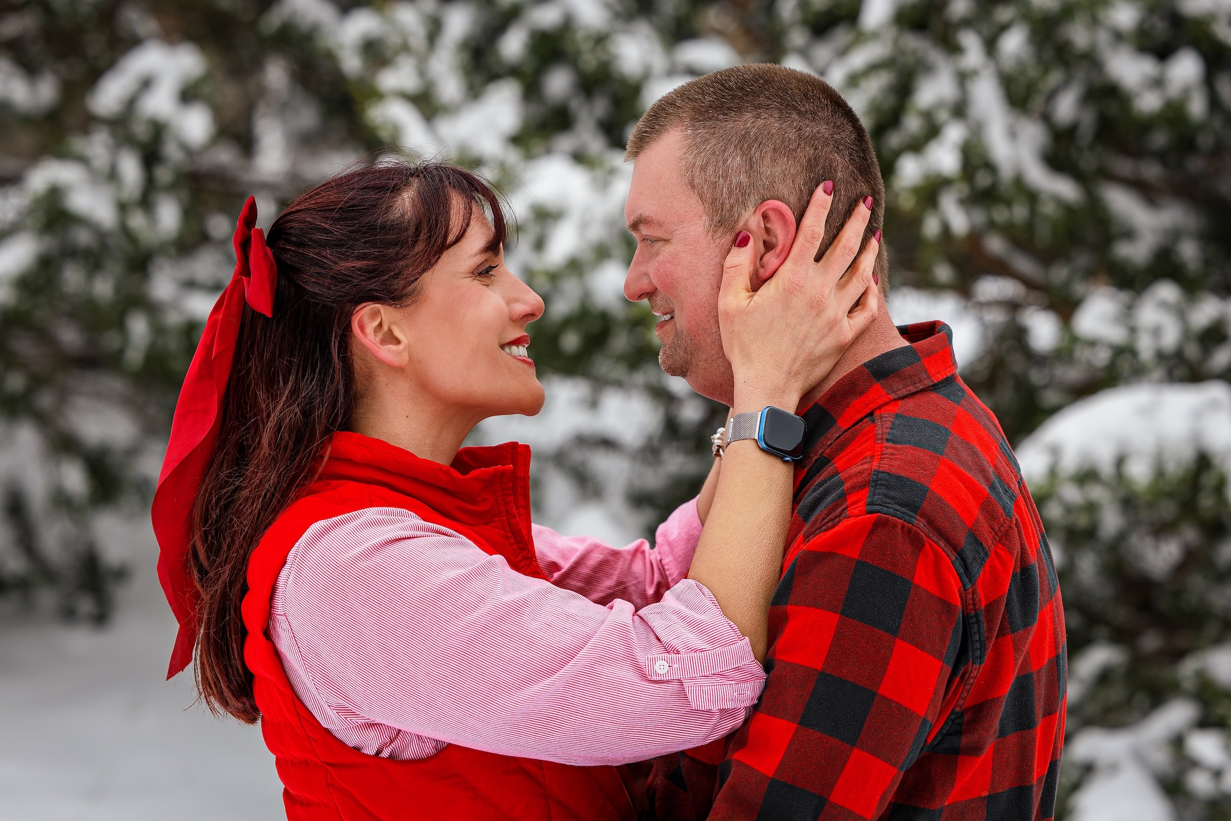 Woman holding fiancé's face and both smiling for engagement shoot