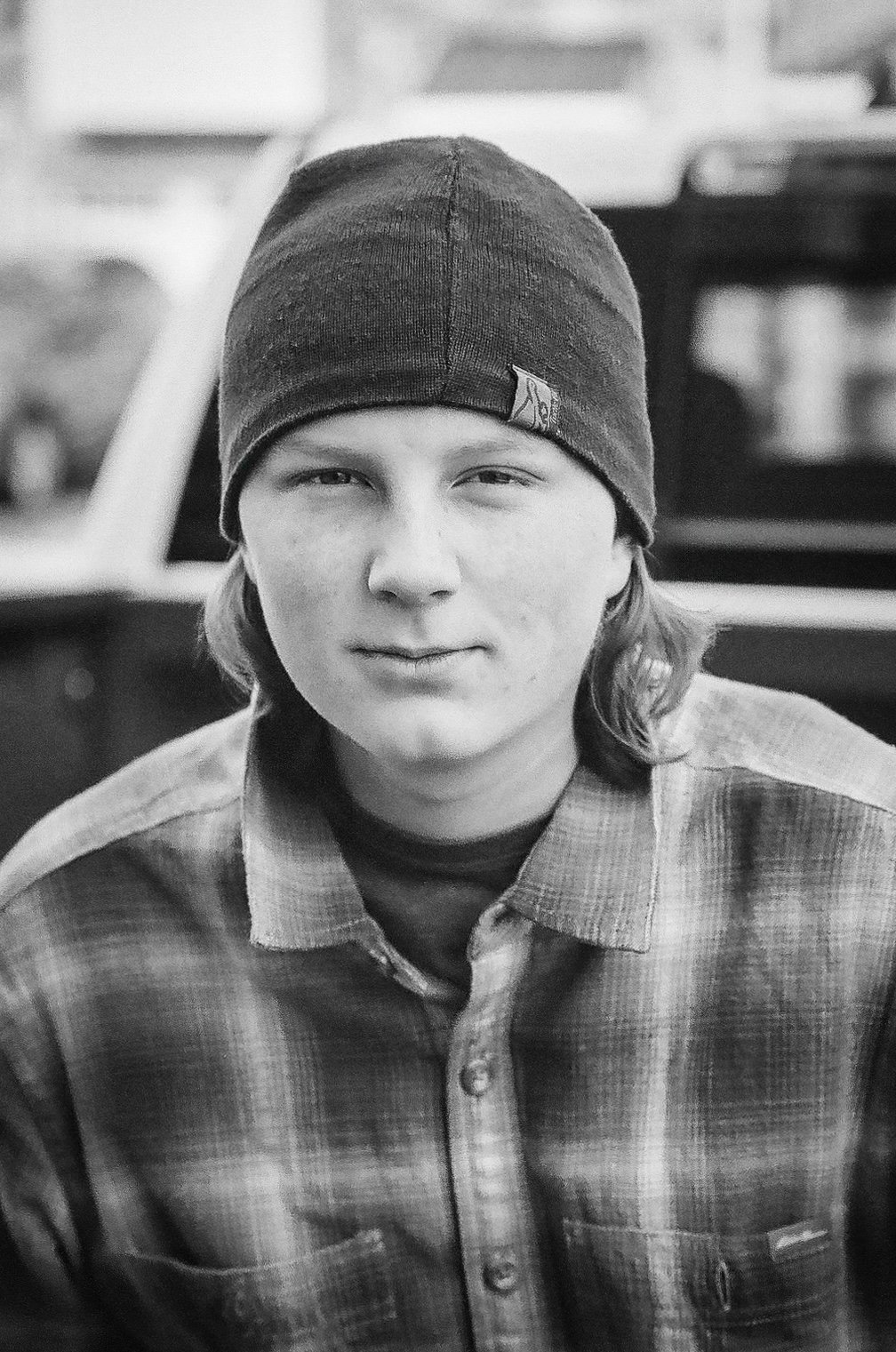 Teenage boy smirking, wearing a beanie and plaid shirt