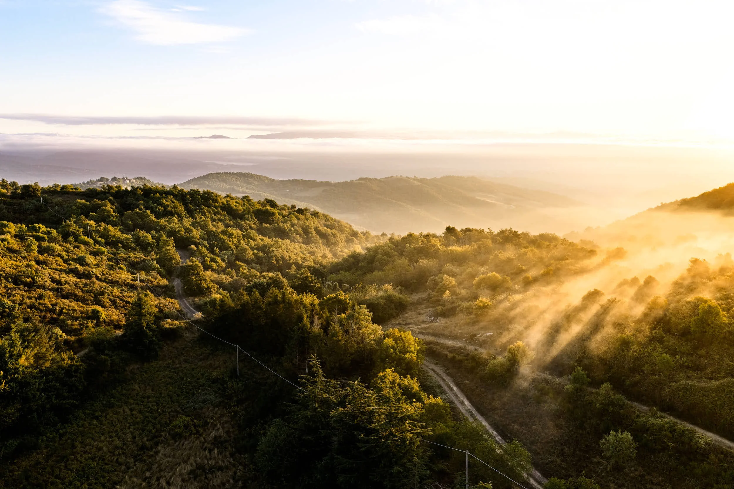 Landschaft mit Sonne, Bäumen und Bergen, Sonnenstrahlen durchdringen die Wolken