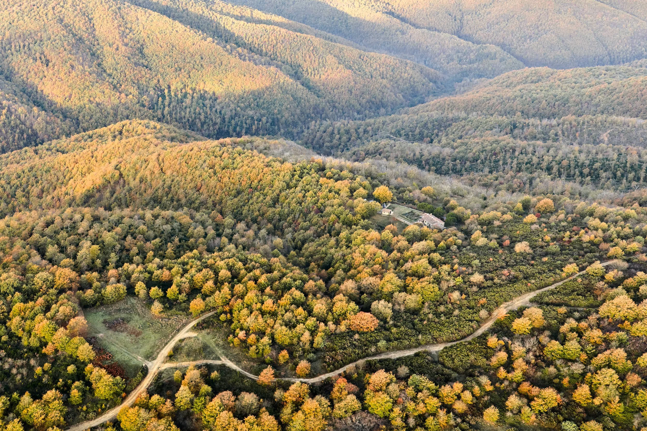 Landschaft mit bewaldeten Hügeln und einem kleinen Haus auf den Hügeln, umgeben von Wäldern im Herbst in Deutschland