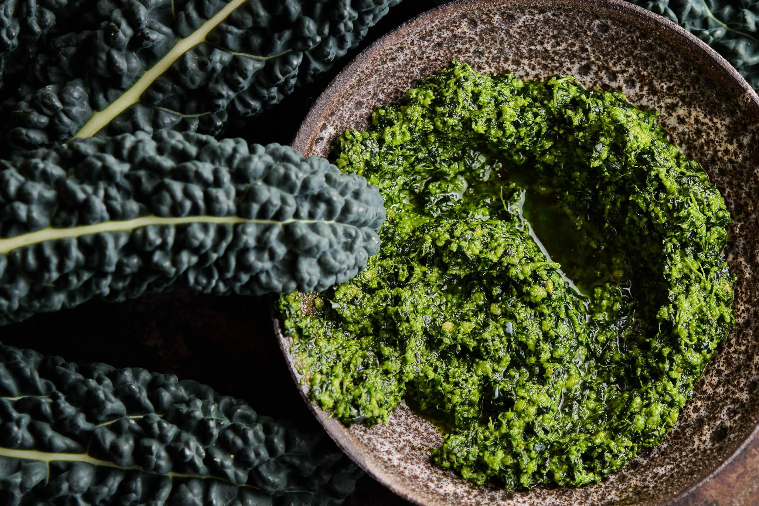 Grüner Mangold in einer Schüssel, umgeben von mehreren rotem Mangoldblättern.