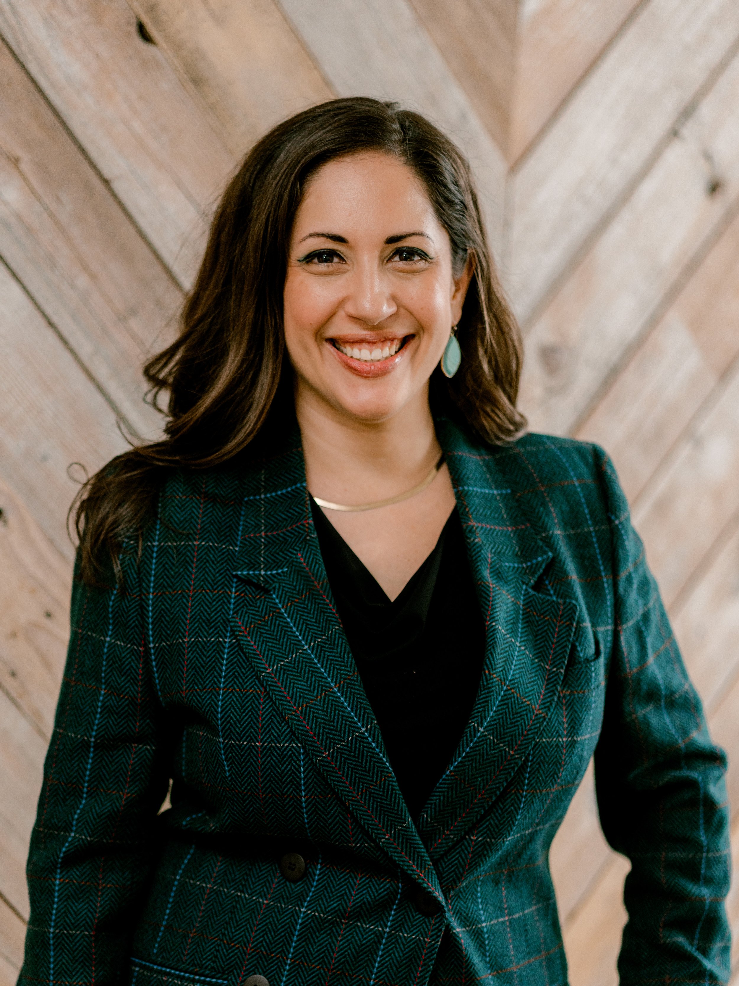Image of a smiling woman with long hair, wearing a suit.