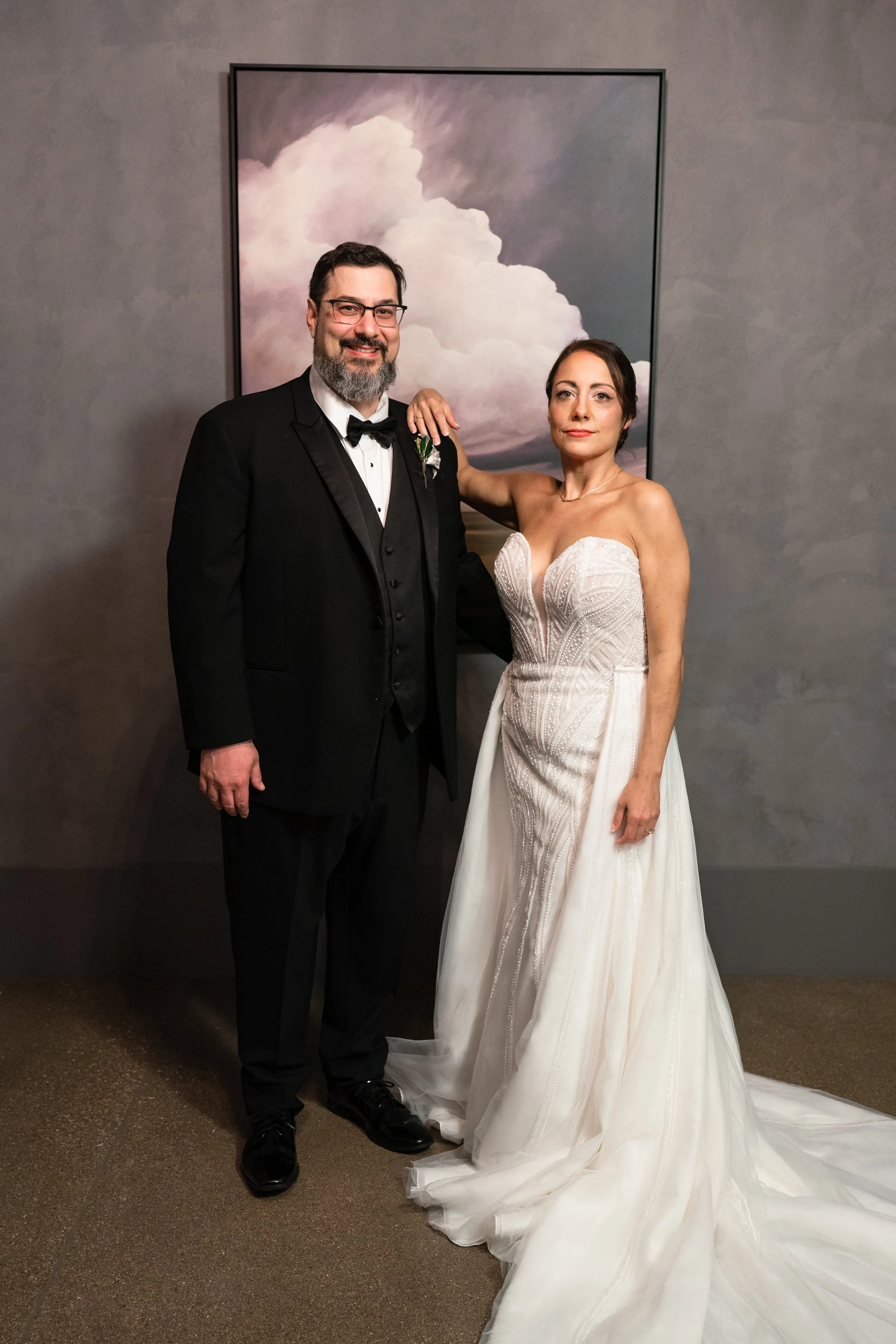 bride and groom posing in front of photo of clouds at The Crawford venue