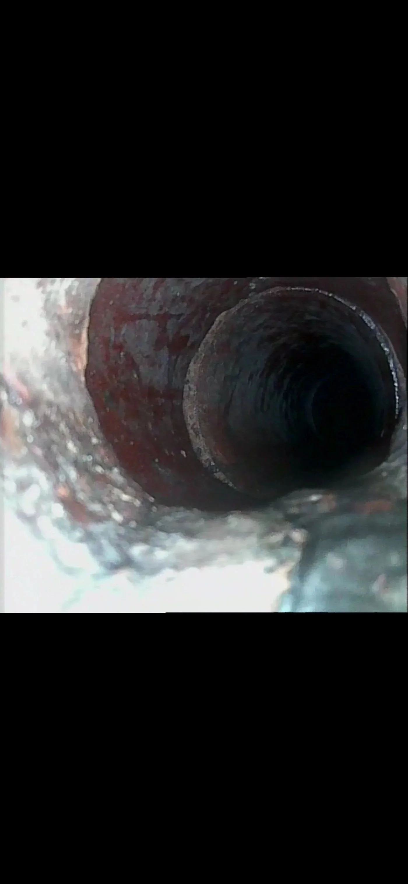 Close-up view of a metal sewer pipe, showing interior with rust and corrosion