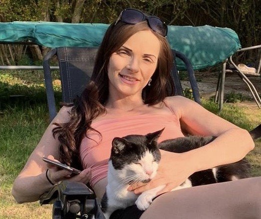 Women sitting outside holding a black and white cat