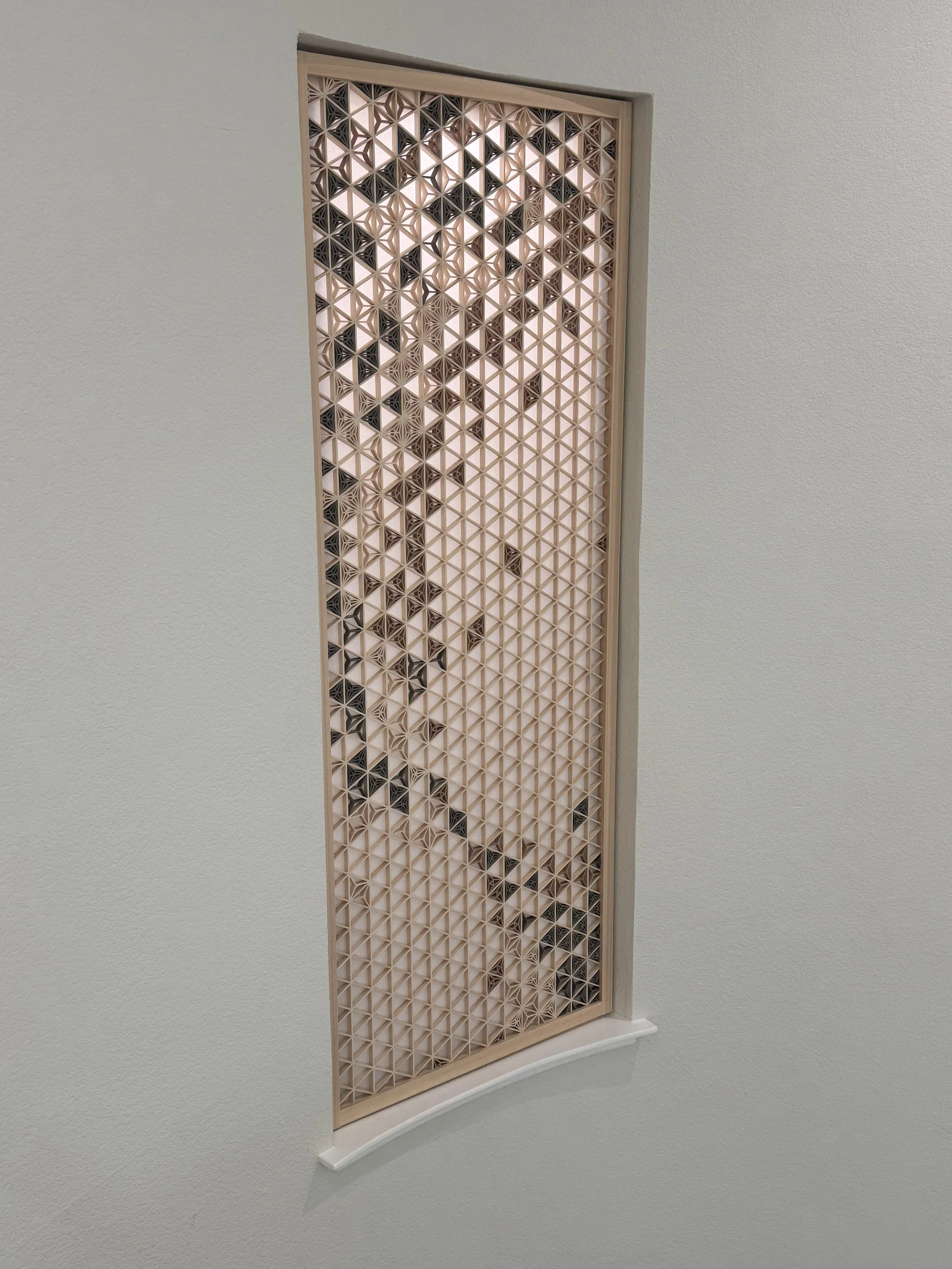 Decorative wooden panel with geometric star pattern mounted on a white wall.