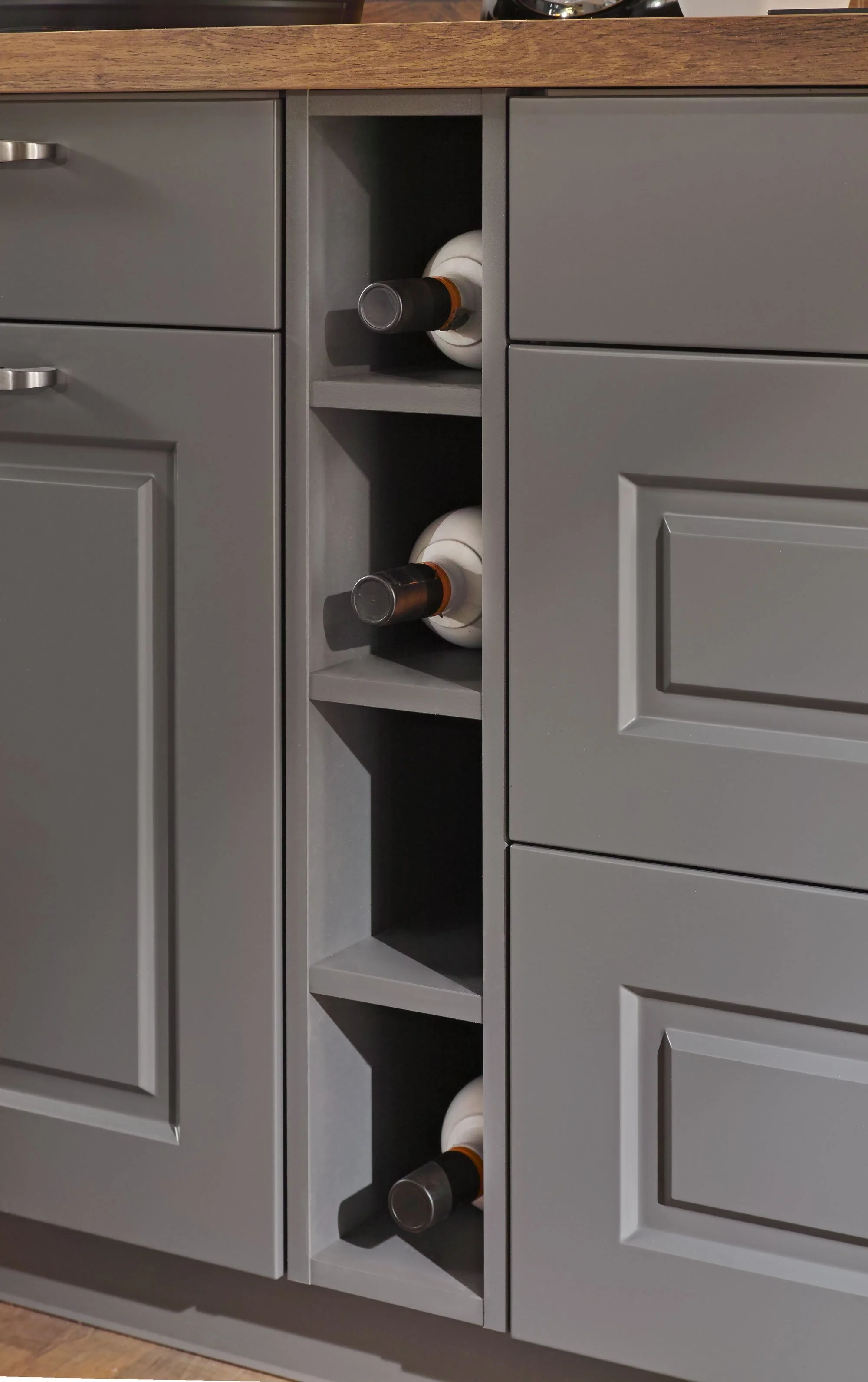 Gray kitchen cabinet with a built-in wine rack holding three bottles of wine.