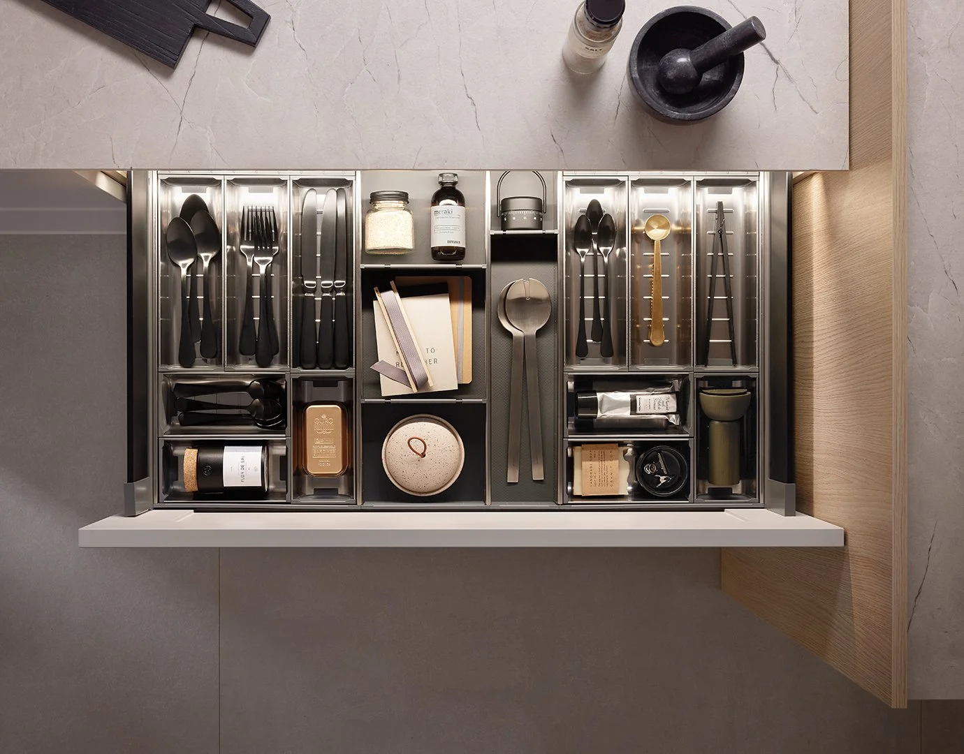 Top view of an organized kitchen drawer with utensils, containers, and small kitchen tools in compartments.