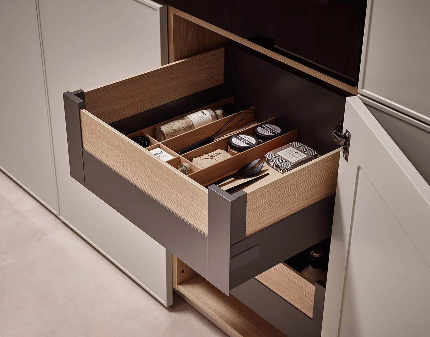 Open kitchen drawer containing spices, kitchen utensils, and small packs of food items.